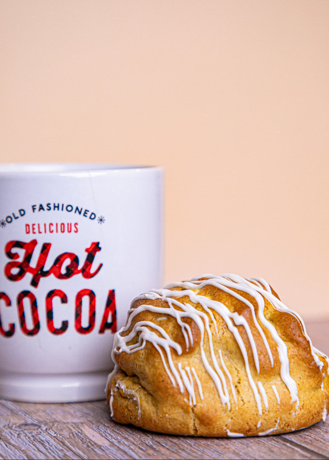 White mug next to a Golden Pumpkin cookie with white chocolate chips and salted caramel filling on a wooden surface, cozy fall treat.