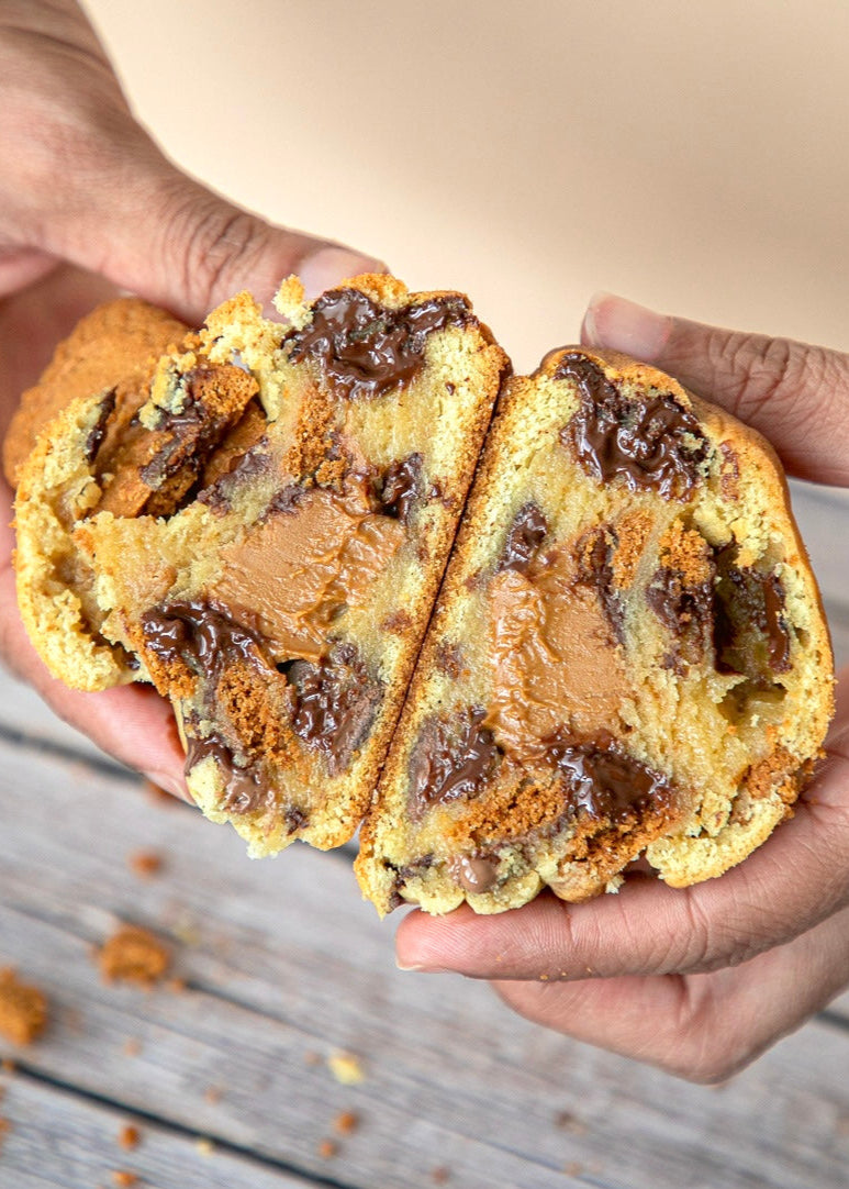 Person holding a chocolate chip cookie with visible chocolate chunks and biscoff swirls.